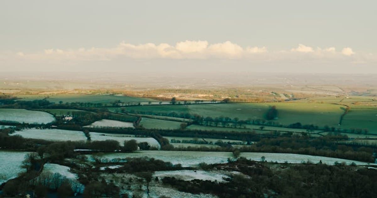 A stunning aerial capture of frosty farmlands showcasing winter's beauty.