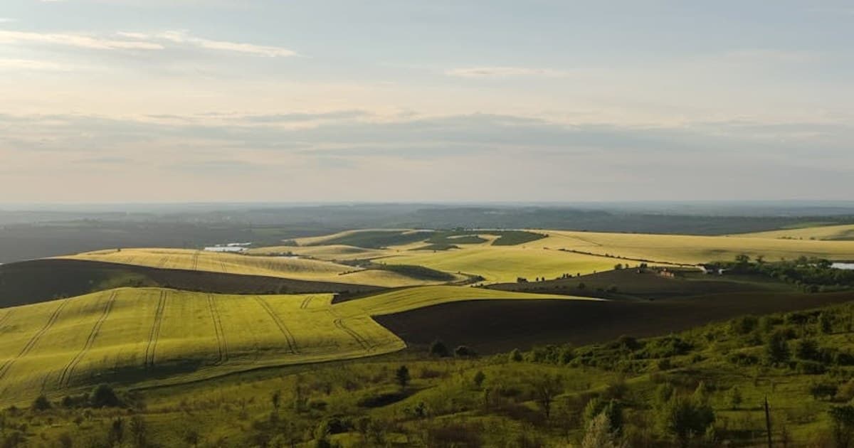 Breathtaking view of rolling hills and fields under a dramatic sunset sky near Chernovtsy, Ukraine.