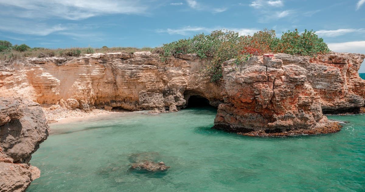 Explore the stunning coastal rock formations and turquoise waters of Cabo Rojo, Puerto Rico under a bright summer sky.