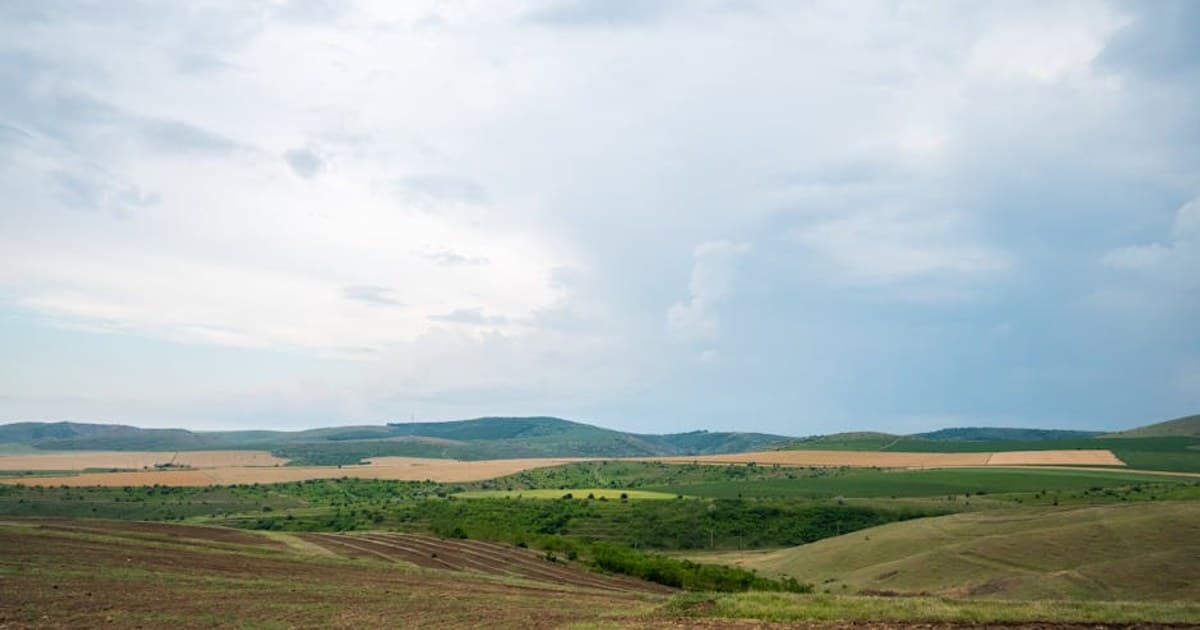 Vast rolling hills under a cloudy sky in the Romanian countryside.