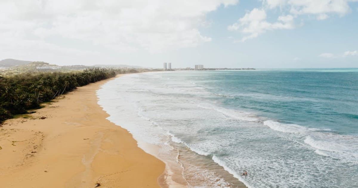 Golden sand beach in Puerto Rico with gentle waves, ideal for a tropical summer vacation.