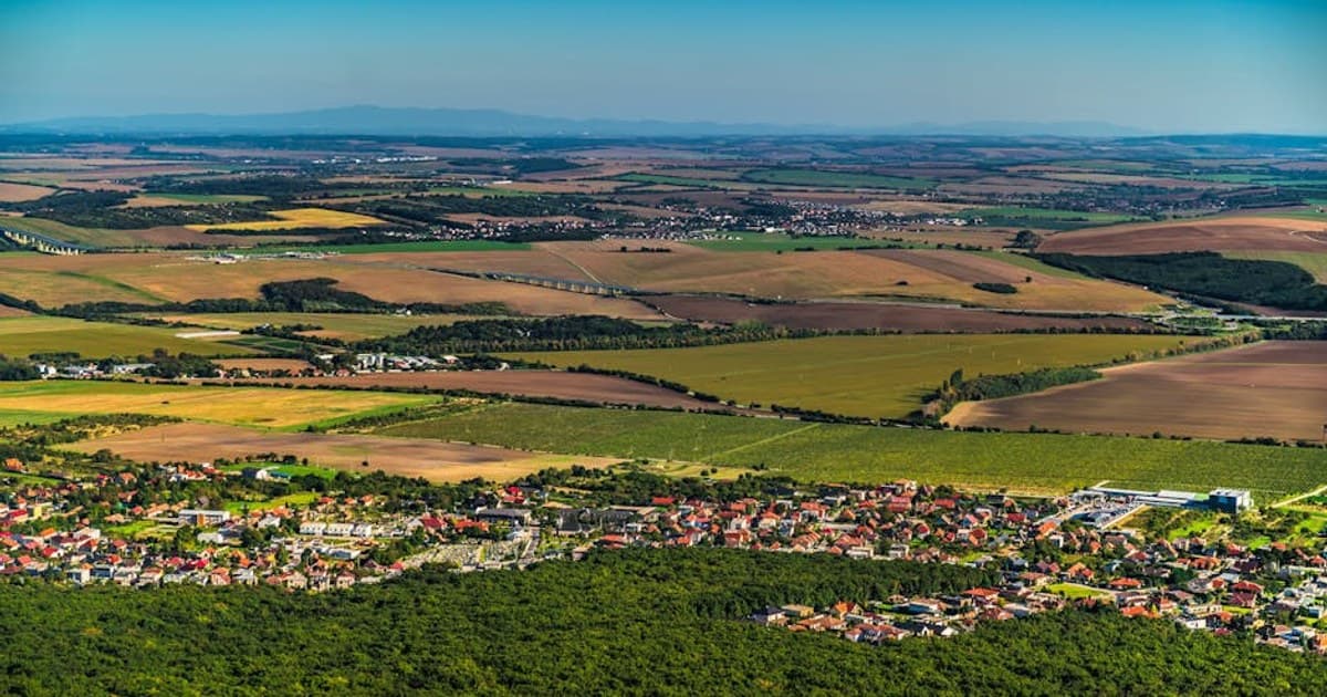 Expansive aerial view showcasing lush green fields and villages near Nitra, Slovakia on a sunny summer day.
